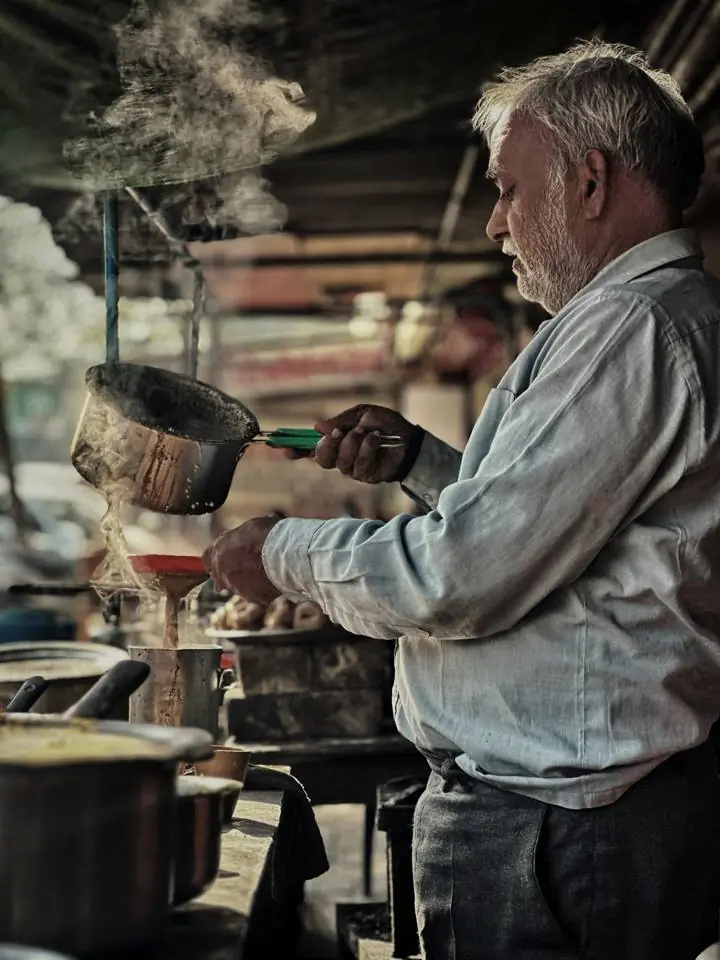 A tea seller pouring chai
